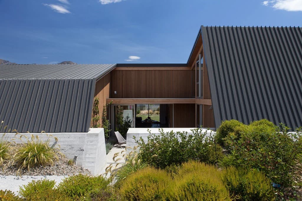 Modern New Zealand home with wood and metal exterior against mountain backdrop